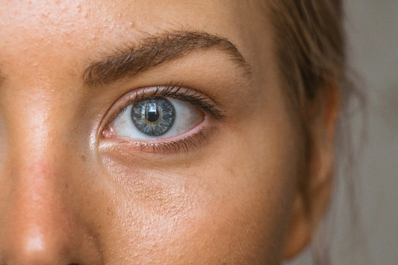 Editorial close-up of a blue eye and natural eyebrow