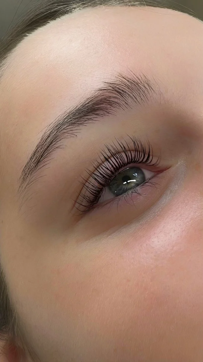 Close-up of upward-curled lashes beside a blue eye